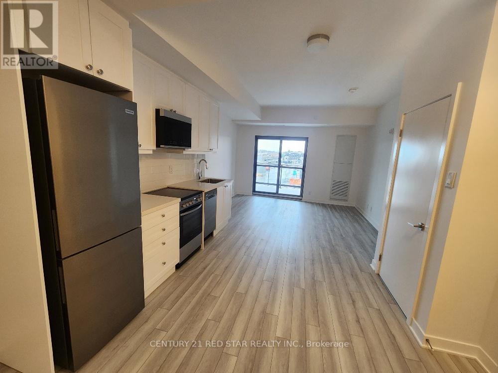 A kitchen with a refrigerator, oven, and microwave.
