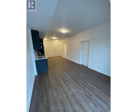 A spacious room with wooden flooring and white walls.
