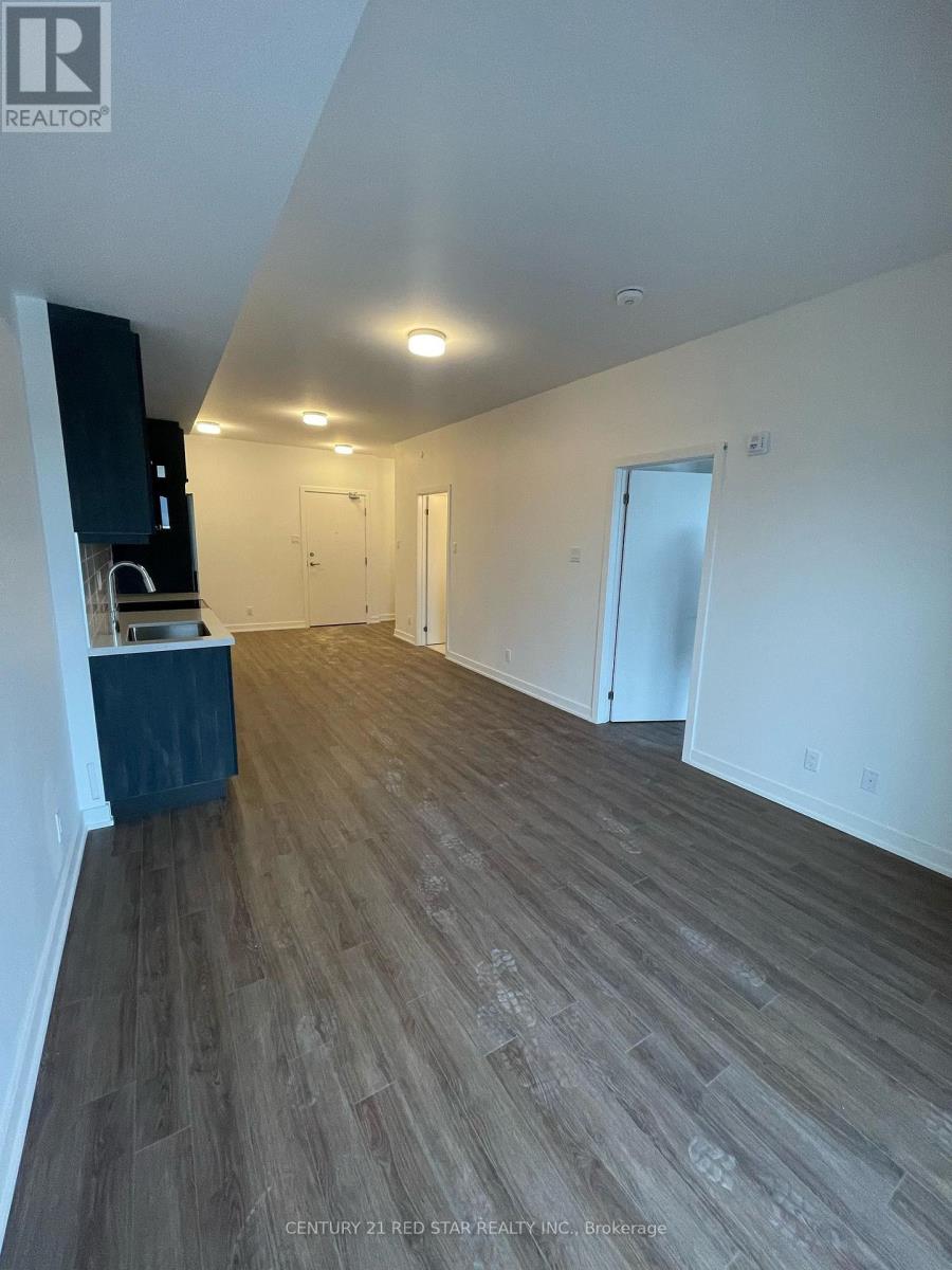 A room with wooden flooring and white walls, with a cabinet and a countertop on the left side.