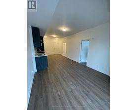 A room with wooden flooring and white walls, with a cabinet and a countertop on the left side.