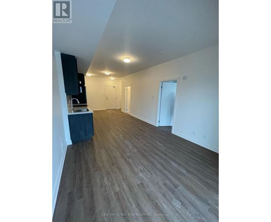 A room with wooden flooring and white walls, with a cabinet and a countertop on the left side.