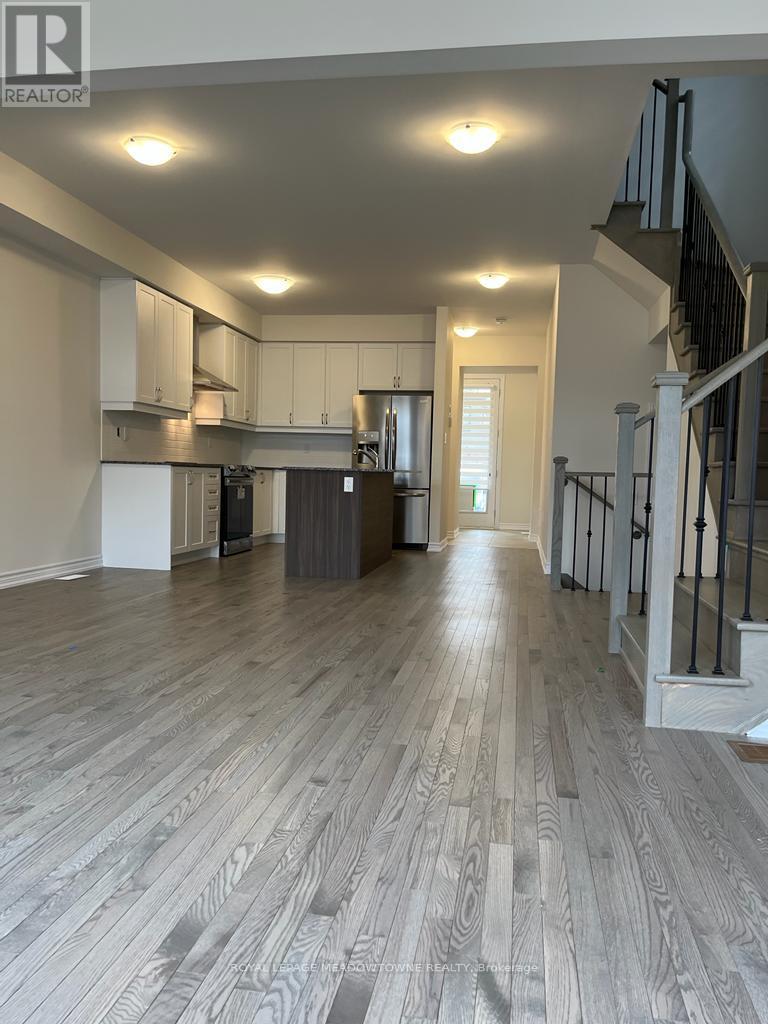 A spacious room with wooden flooring and a staircase on the right side.