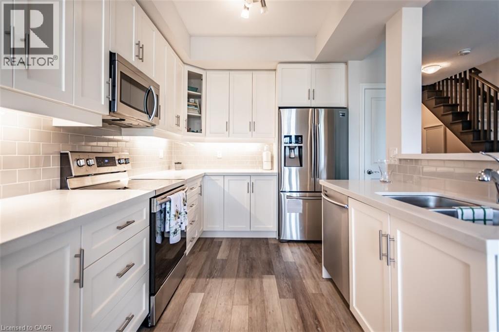 A kitchen with white cabinets and a stainless steel refrigerator.