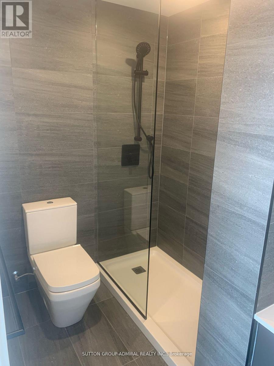 A white toilet sits next to a glass shower stall in a bathroom.