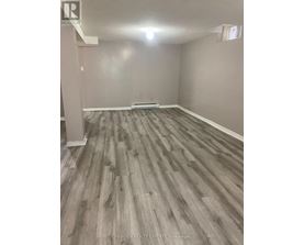 A room with wooden flooring and a white column in the corner.