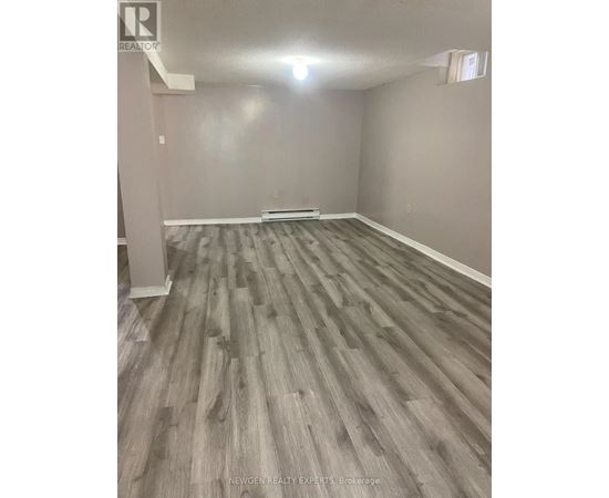 A room with wooden flooring and a white column in the corner.