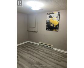 A room with a grey floor and a painting on the wall.