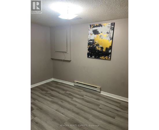 A room with a grey floor and a painting on the wall.