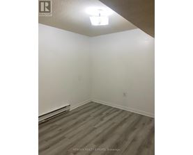 A room with wooden flooring and white walls.