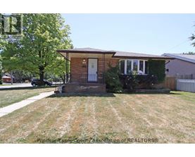 A house with a front yard and a tree in front of it.