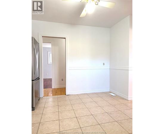 A kitchen with a refrigerator and a doorway leading to another room.