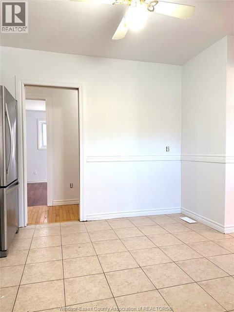 A kitchen with a refrigerator and a doorway leading to another room.