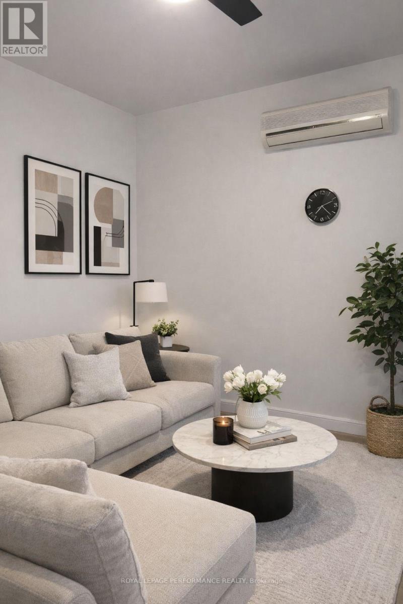 A living room with a grey couch, a white coffee table, and a plant.