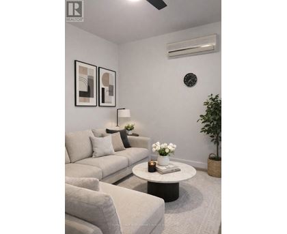 A living room with a grey couch, a white coffee table, and a plant.
