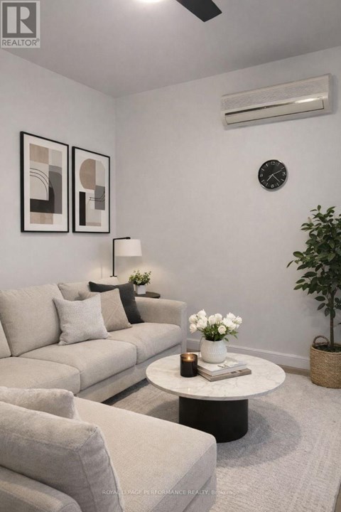A living room with a grey couch, a white coffee table, and a plant.