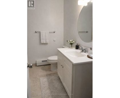 A white bathroom with a toilet, sink, and mirror.