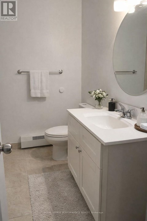 A white bathroom with a toilet, sink, and mirror.