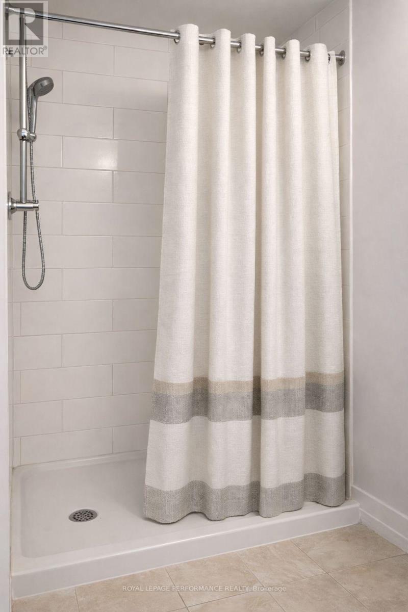 A white shower curtain with grey stripes hangs in a white tiled shower.
