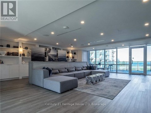 A modern living room with a grey sofa and a glass door leading to a balcony.