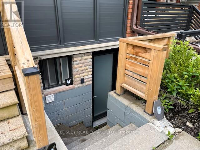A wooden staircase with a metal railing leads up to a window on a building.