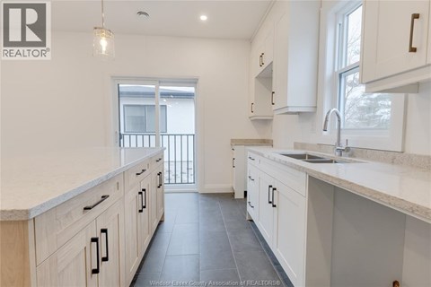 A kitchen with white cabinets and a marble countertop.