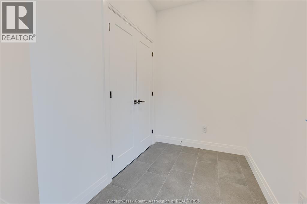 A room with a white door and a grey floor.