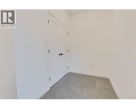 A room with a white door and a grey floor.