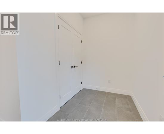A room with a white door and a grey floor.