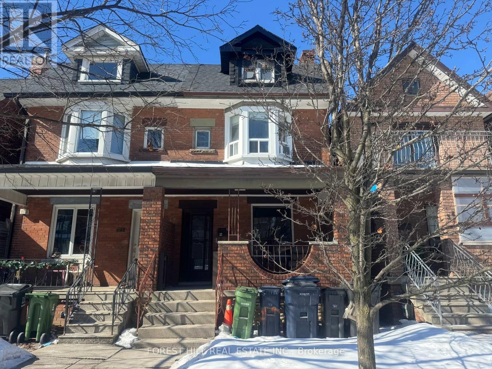 A large brick house with a black door and a tree in front.