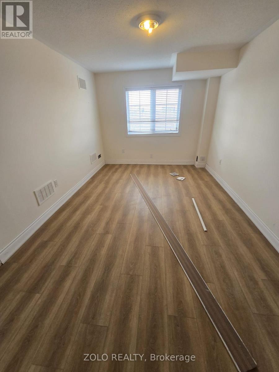 A room with wooden flooring and a window with blinds.