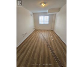 A room with wooden flooring and a window with blinds.