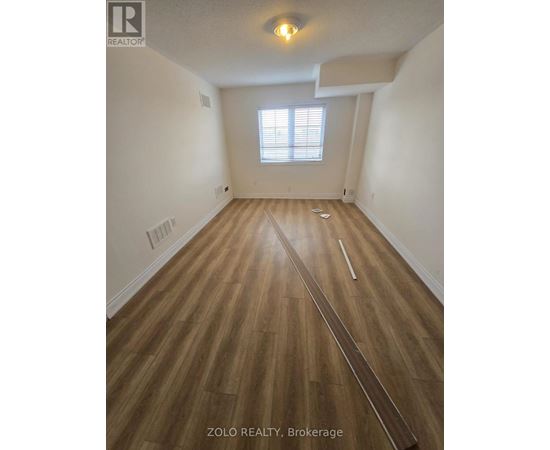 A room with wooden flooring and a window with blinds.