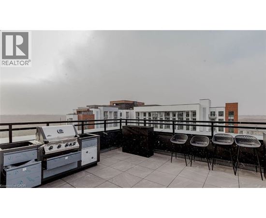 A balcony with barbecue grills and chairs overlooking a cityscape.