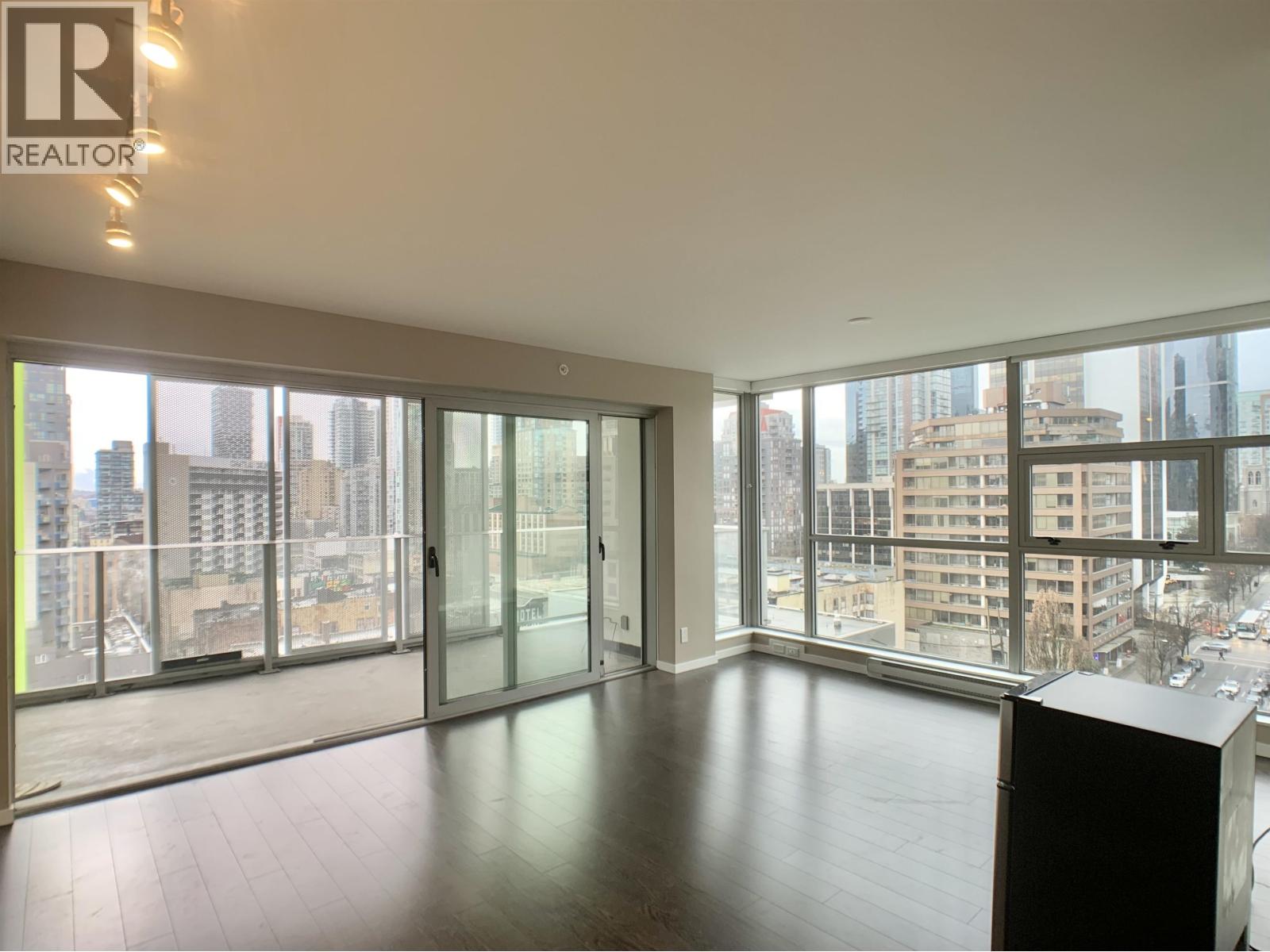 A large, empty room with a view of the cityscape outside the windows.