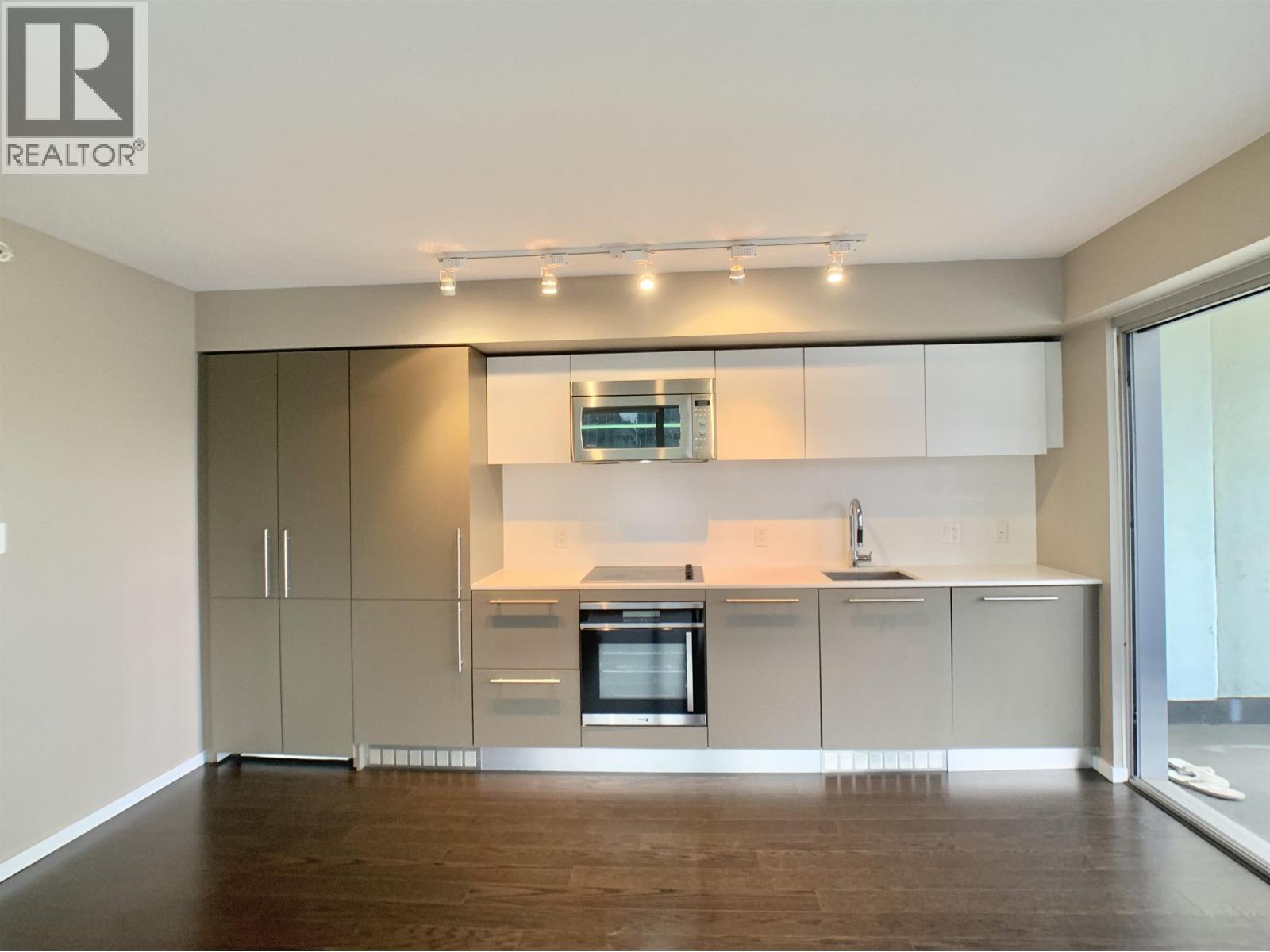 A modern kitchen with wooden floors and white cabinetry.