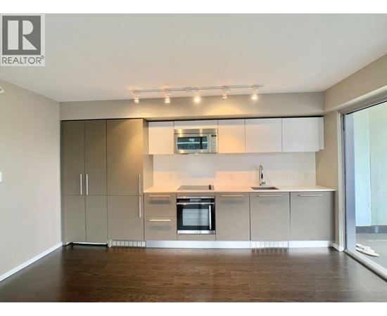 A modern kitchen with wooden floors and white cabinetry.