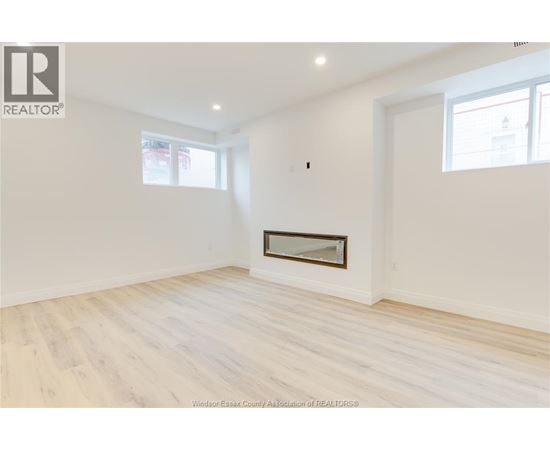 A white room with a fireplace and wood flooring.