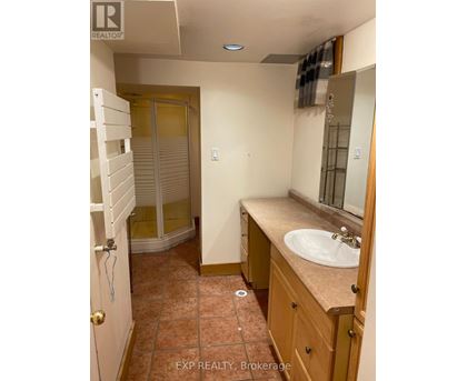 A bathroom with a sink, mirror, and a shower with a glass door.