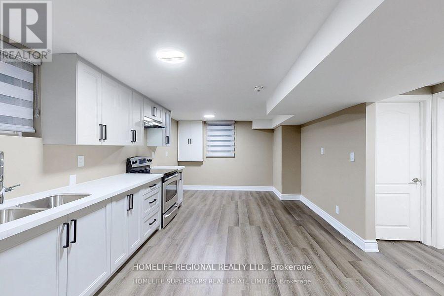 A spacious kitchen with white cabinets and a wooden floor.