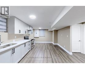 A spacious kitchen with white cabinets and a wooden floor.