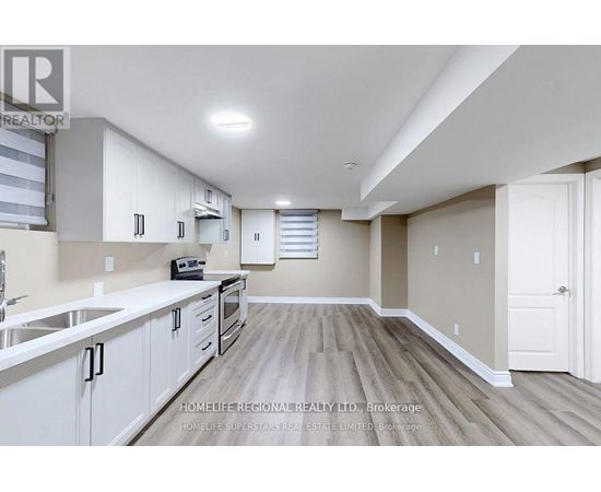 A spacious kitchen with white cabinets and a wooden floor.