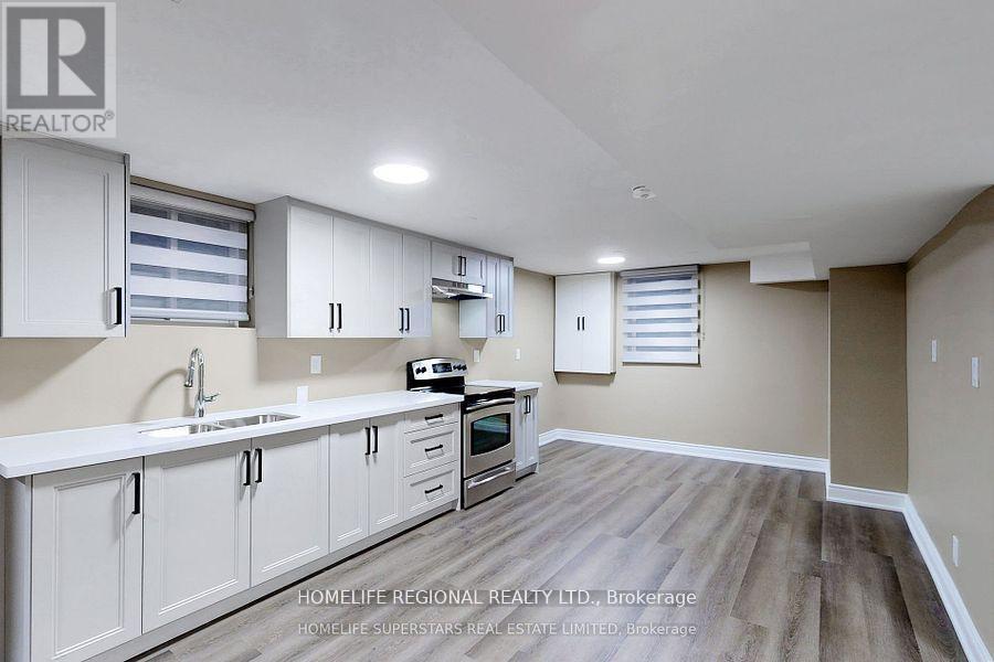 A kitchen with white cabinets and a wooden floor.