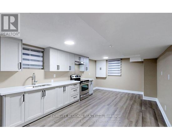 A kitchen with white cabinets and a wooden floor.