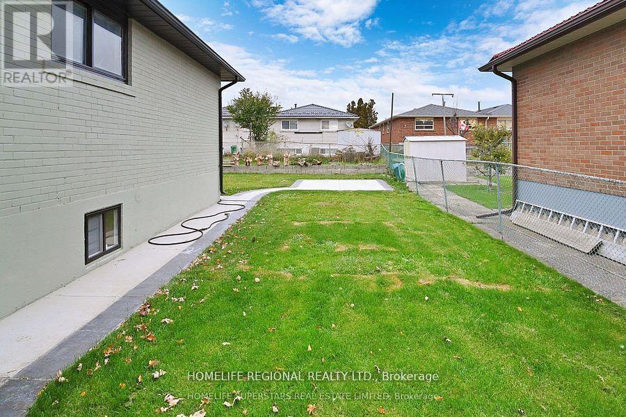A backyard with a fence and a grassy area.