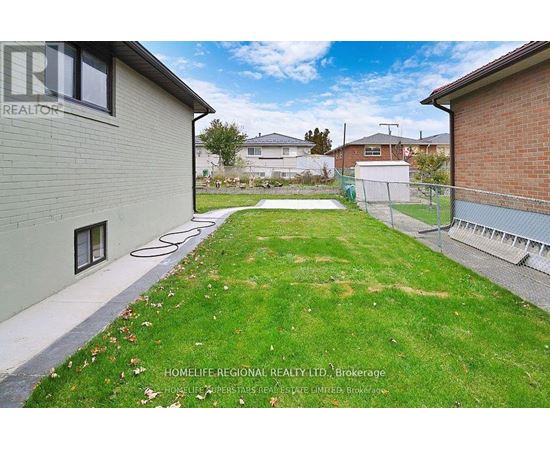 A backyard with a fence and a grassy area.