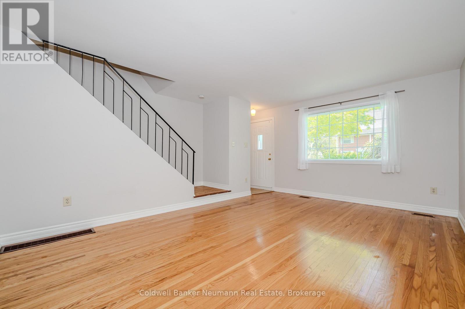 A room with wooden floors and a staircase leading to another room.