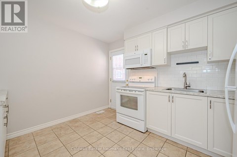 A kitchen with white cabinets and appliances.