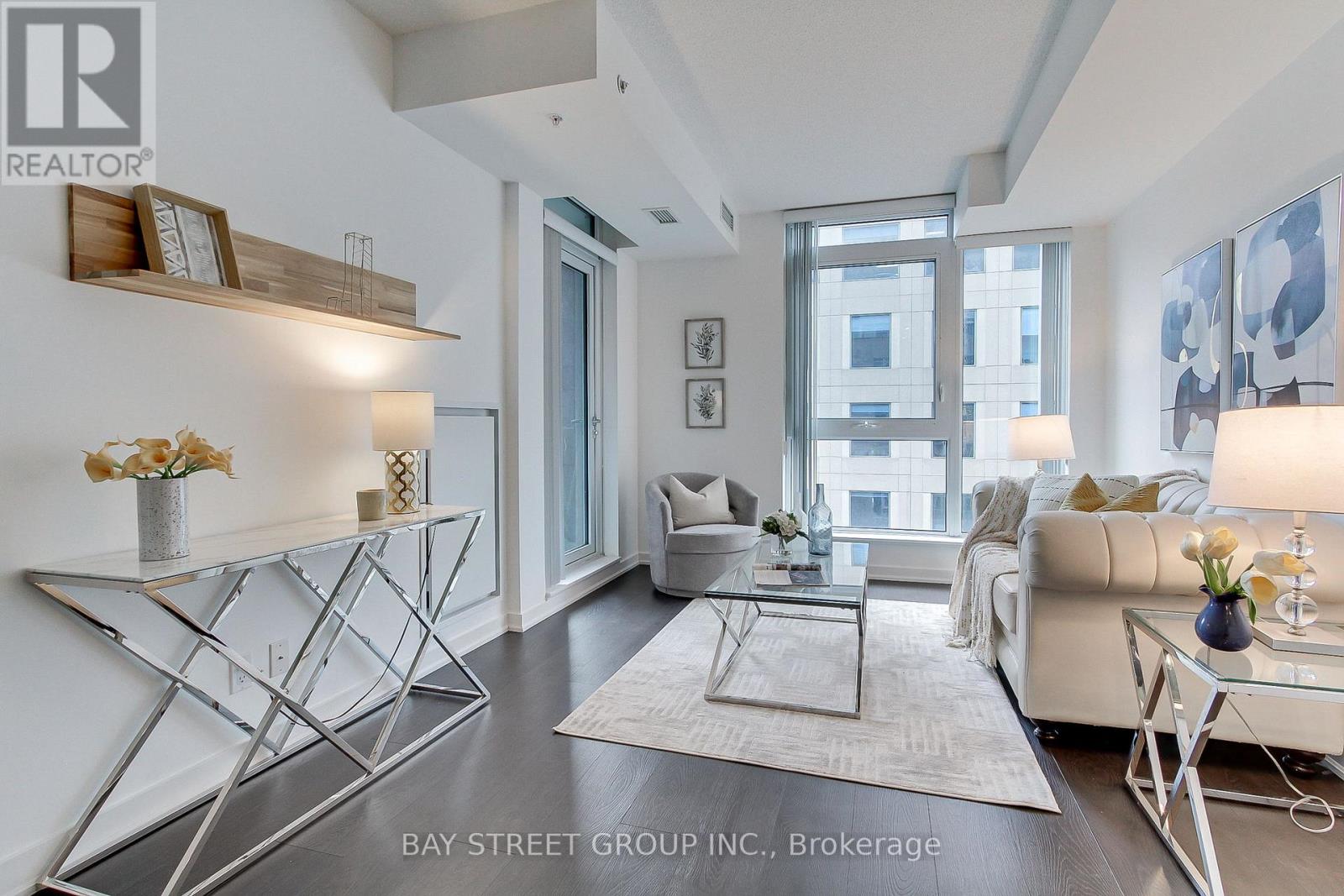 A modern living room with a glass table and white couches.