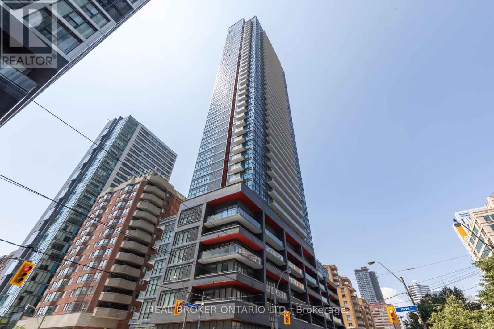 A tall building with a glass facade stands in front of other buildings.