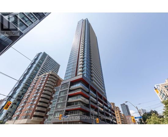 A tall building with a glass facade stands in front of other buildings.